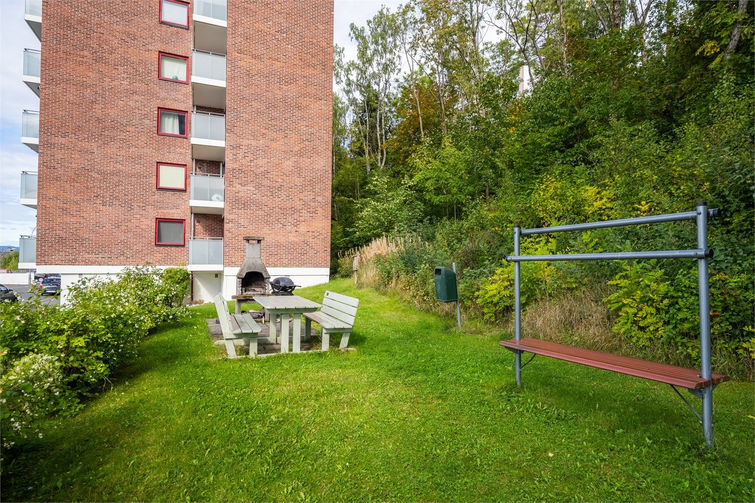 Felles opparbeidet uteområde med plen, sittebenker og grillplass.