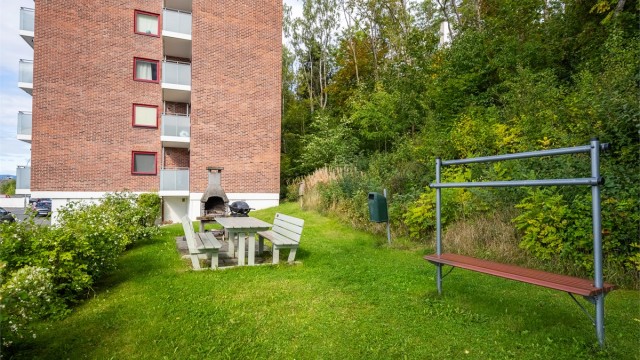 Felles opparbeidet uteområde med plen, sittebenker og grillplass.