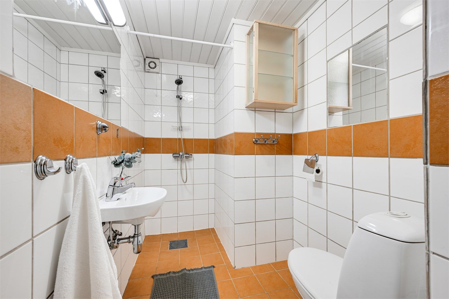 Bad i underetasjen med flislagte overflater, toalett og dusjnisje.