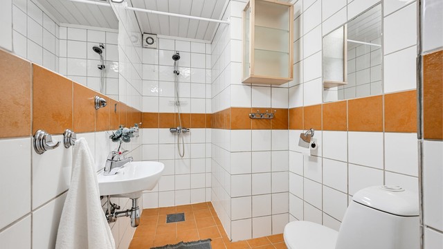 Bad i underetasjen med flislagte overflater, toalett og dusjnisje.