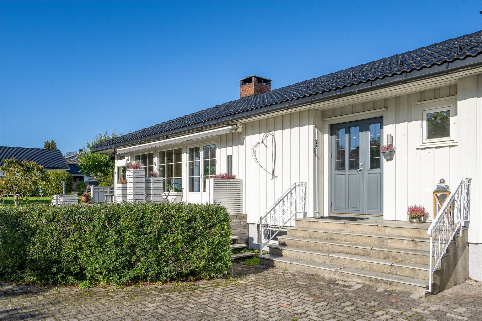 hyggelig inngangsparti med trapp og smijernsrekkverk.