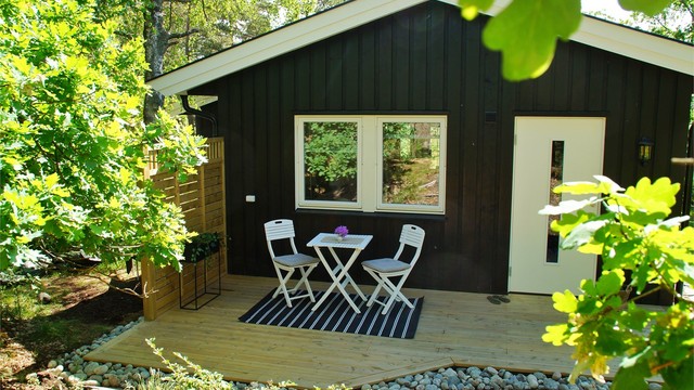Selgers private bilde: Hybelens terrasse er orientert i vestlig retning og avskjermet fra hoveddelens utearealer. Gangvei leder direkte mellom terrassen og biloppstillingsplassen nederst i hagen.