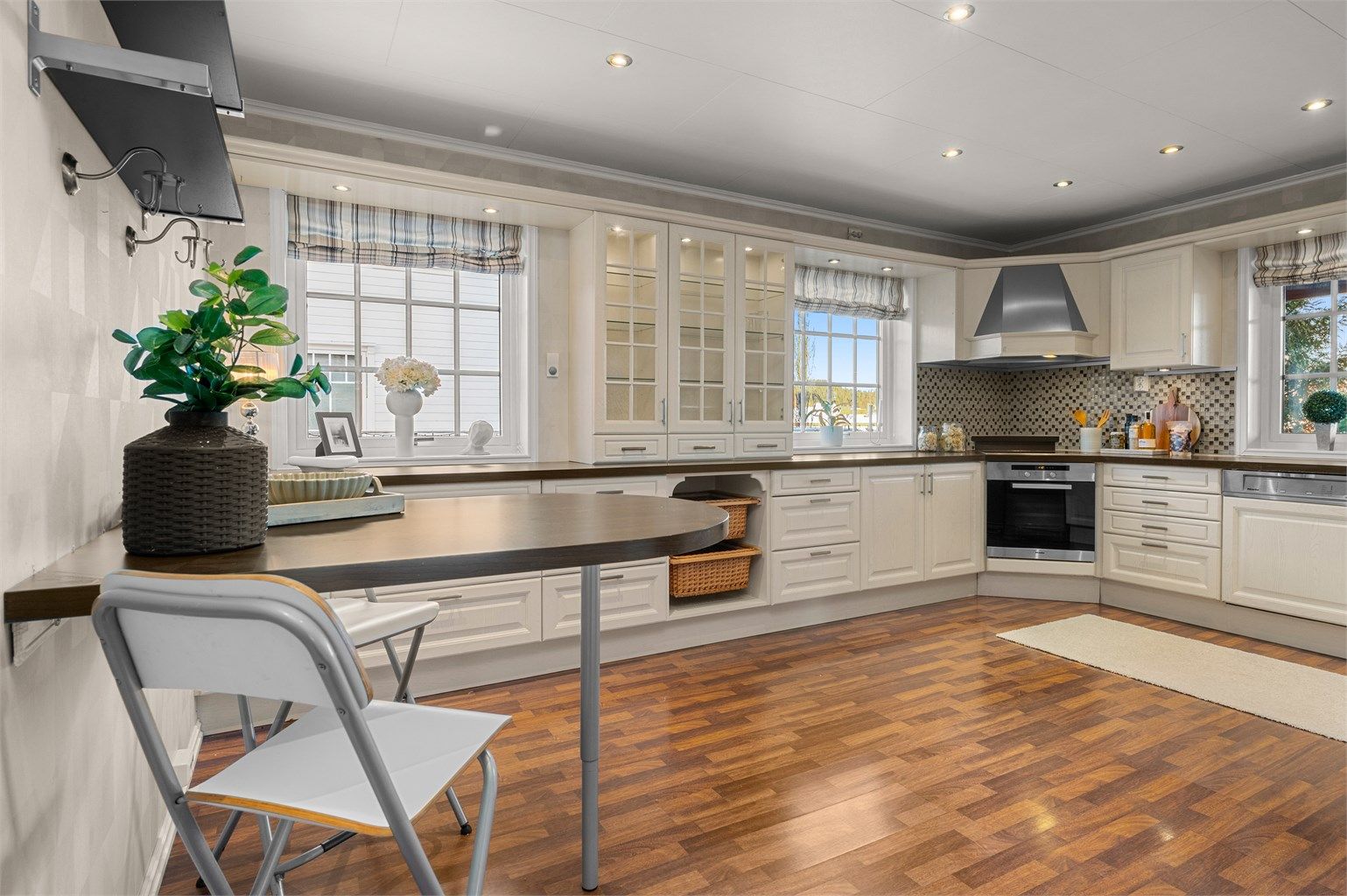 Kjøkkenet ligger naturlig tilbaketrukket fra stuen og er innredet med lyse profilerte flater og benkeplate i kontrast. 