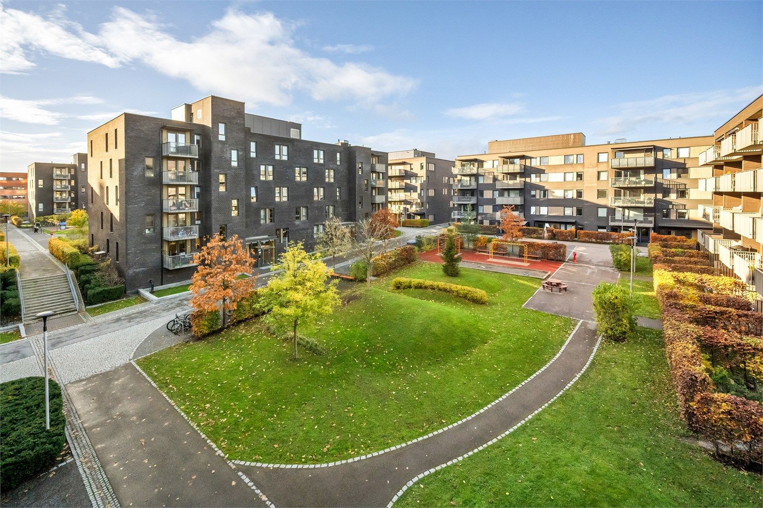 Utsikt over sameiets grønne fellesarealer med lekeplass og beplantning. Her kan du fra høyde følge med når de minste er ute og leker. 