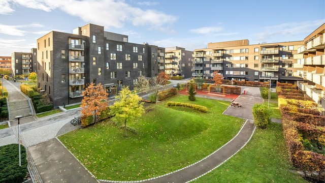 Utsikt over sameiets grønne fellesarealer med lekeplass og beplantning. Her kan du fra høyde følge med når de minste er ute og leker.