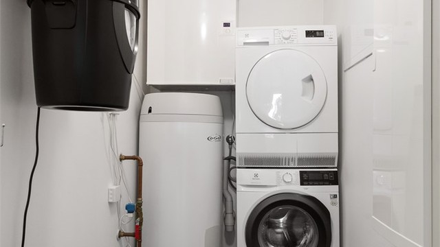 Praktisk innredet rom med opplegg for vaskemaskin. Her er også boligens varmtvannsbereder, sentralstøvsuger og fordelerskap for rør-i-rør-systemet plassert.