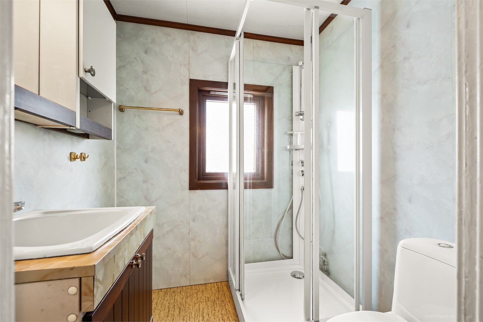 Rommet har baderomsplater på veggene og gulvbelegg.