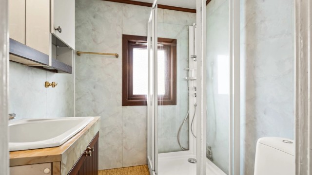 Rommet har baderomsplater på veggene og gulvbelegg.