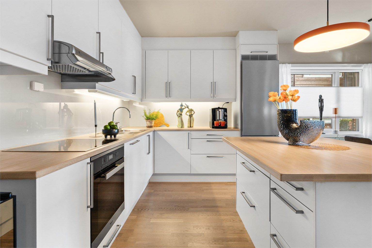 Moderne kjøkken med integrerte hvitevarer og kjøkkenøy.