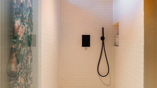 En romslig dusjnisje med flislagte overflater.