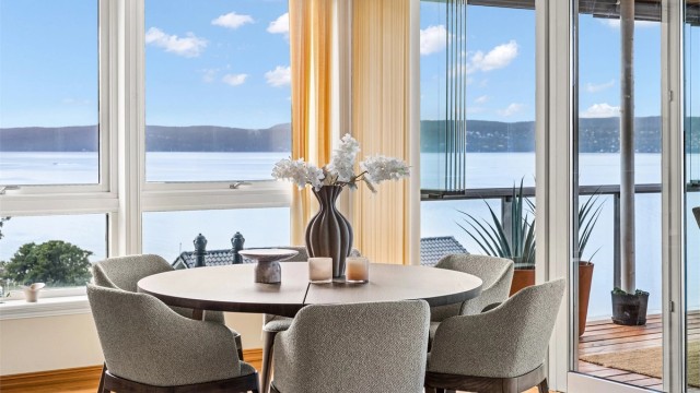Store vinduer fra gulv til tak fremhever den unike utsikten, og skaper en sømløs overgang mellom inne og vannet