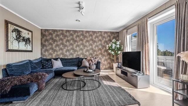 Stuen har god plass til en romslig sofagruppe og utgang til balkongen.