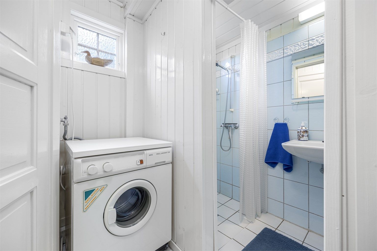 Badet er praktisk innredet med dusjnisje og opplegg for vaskemaskin.