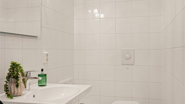 Separat toalettrom med flislagt gulv med gulvvarme, vegghengt toalett og servantinnredning.