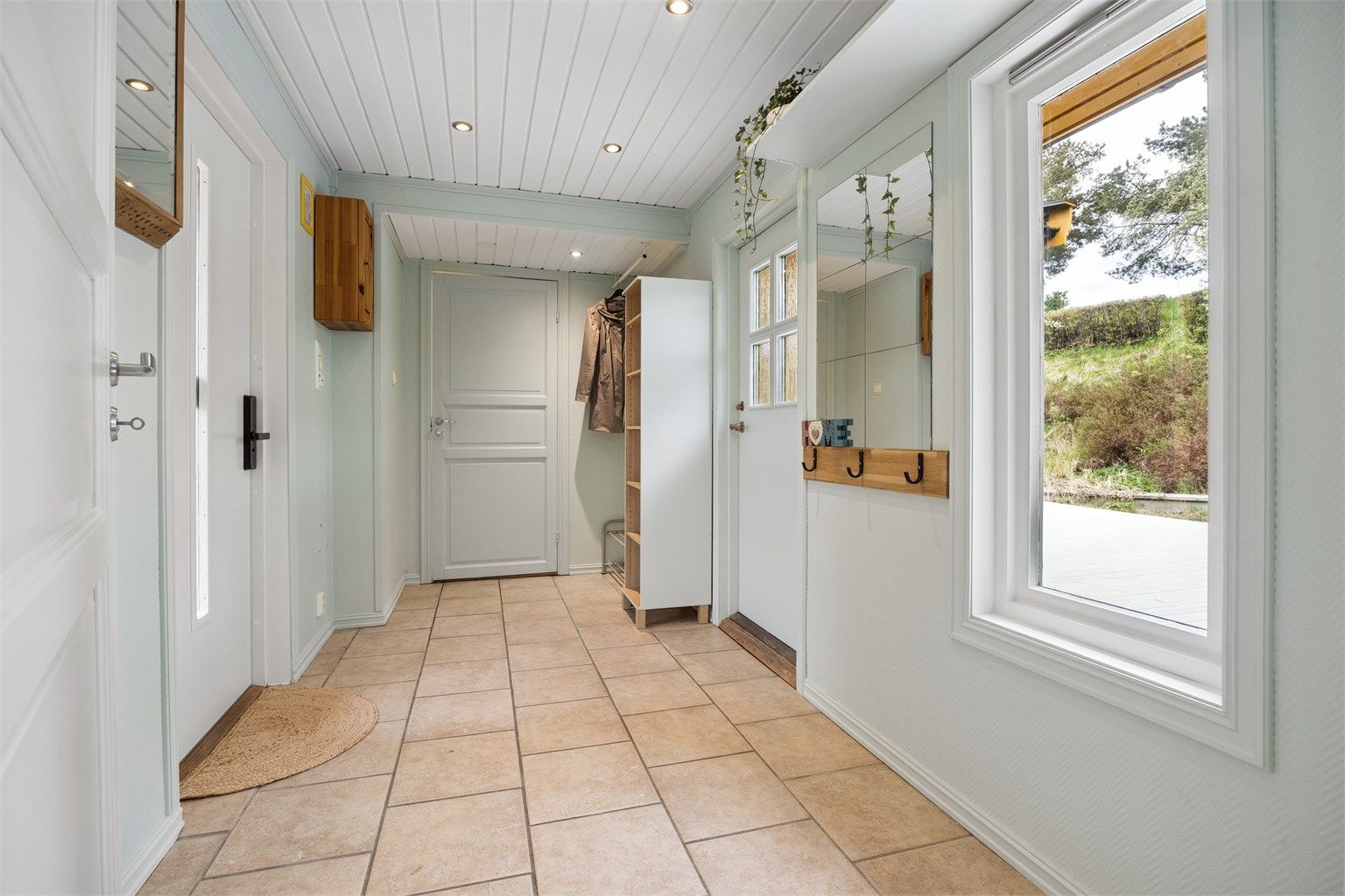 Entré med adkomst til gårdsplassen og til terrasseplatting på baksiden av boligen