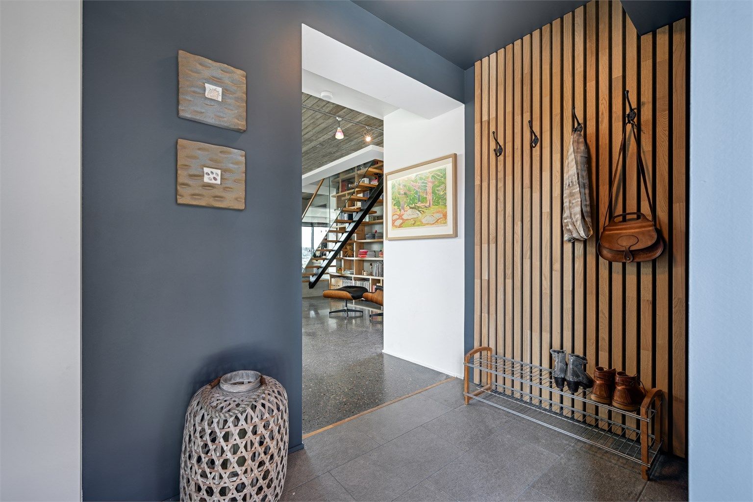 Detaljer som spilevegg i tre gir en varm velkomst og et hint om materialvalgene som går igjen i boligen.