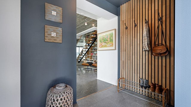 Detaljer som spilevegg i tre gir en varm velkomst og et hint om materialvalgene som går igjen i boligen.