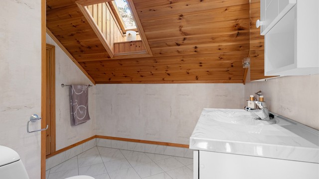 Badets gulv og vegger er utført med henholdsvis fliser og våtromstapet, dusjnisjens vegger er også flislagt. Det er i tillegg varme i gulvet.