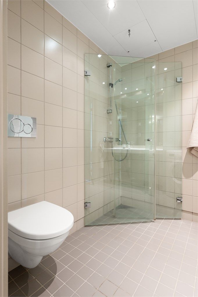 Badet har elektrisk gulvvarme for økt komfort. Innredningen inkluderer vegghengt klosett og dusjhjørne med svingbare glassdører.