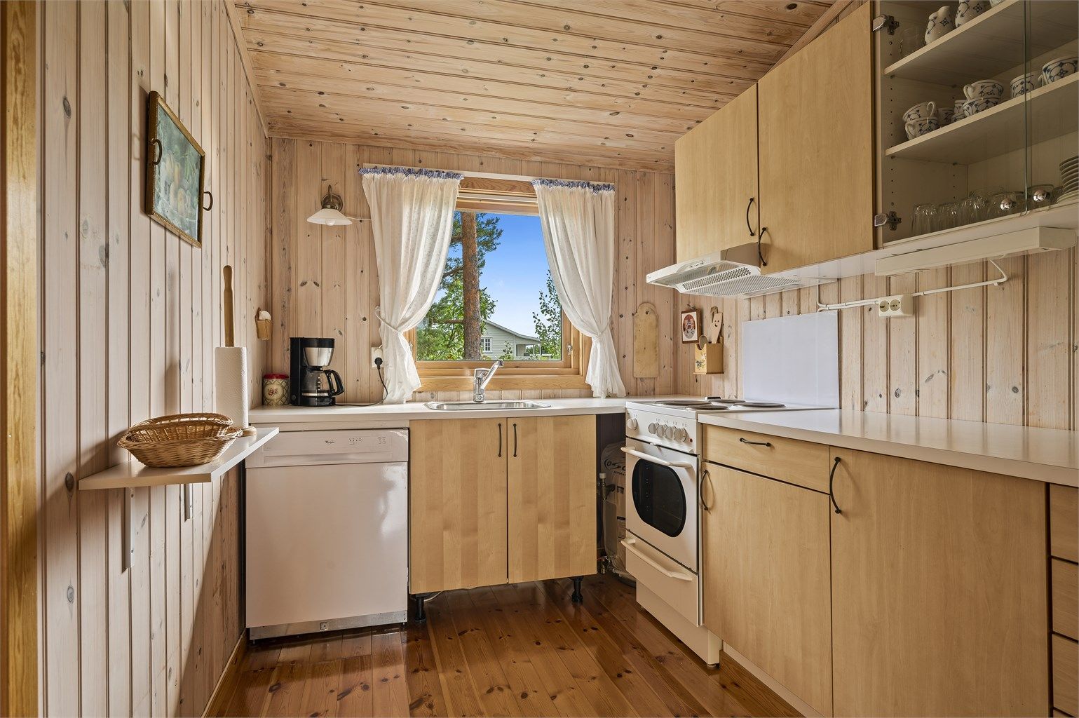 Kjøkken med kjøleskap, komfyr og oppvaskmaskin. 