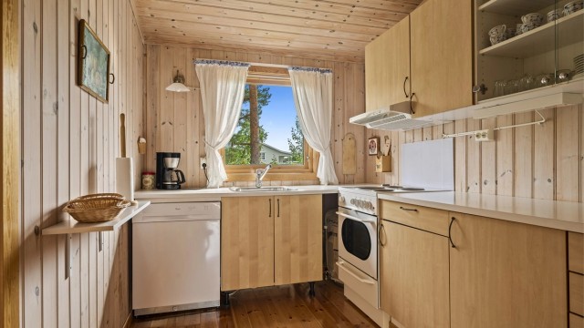 Kjøkken med kjøleskap, komfyr og oppvaskmaskin.