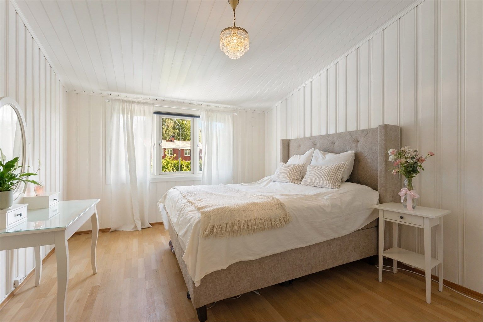 Soverom i andre etasje med malt panel på vegger og tregulv.