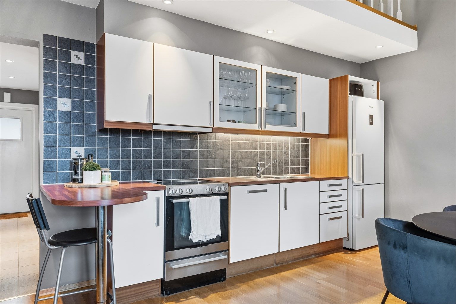 Kjøkken med godt med både skap og benkeplass. Smart løsning med halvøy som gir plass til dagens mindre måltider eller at besøket kan være sosiale ved matlaging.