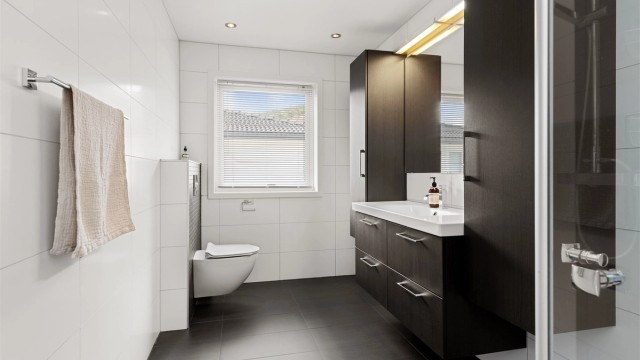 Flislagt bad med varme i gulvet, vegghengt toalett og downlights i taket.