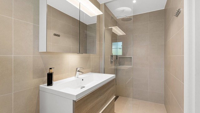 Pent baderom fra 2017 med fliser på gulv med gulvvarme, fliser på vegger og malt himling med downlights