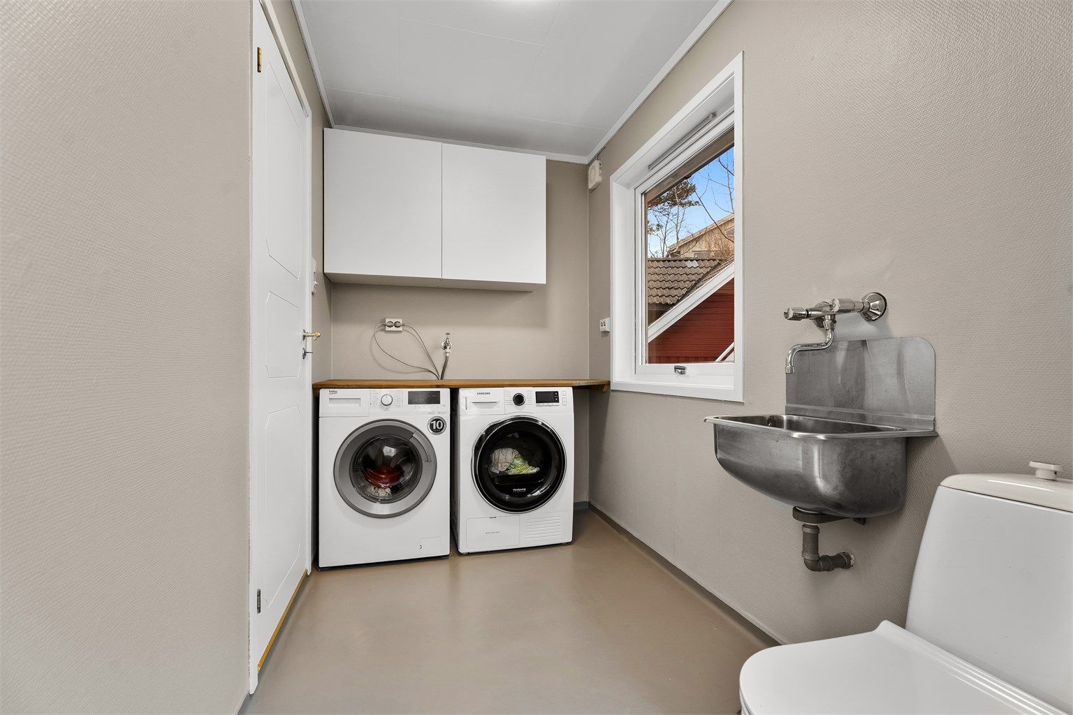 Fra kjøkkenet er det inngang til et praktisk vaskerom med plass til vaskemaskin og tørketrommel. Det er utslagsvask, praktisk arbeidsbenk, toalett og overskap. Egen utgang til siden av huset. 