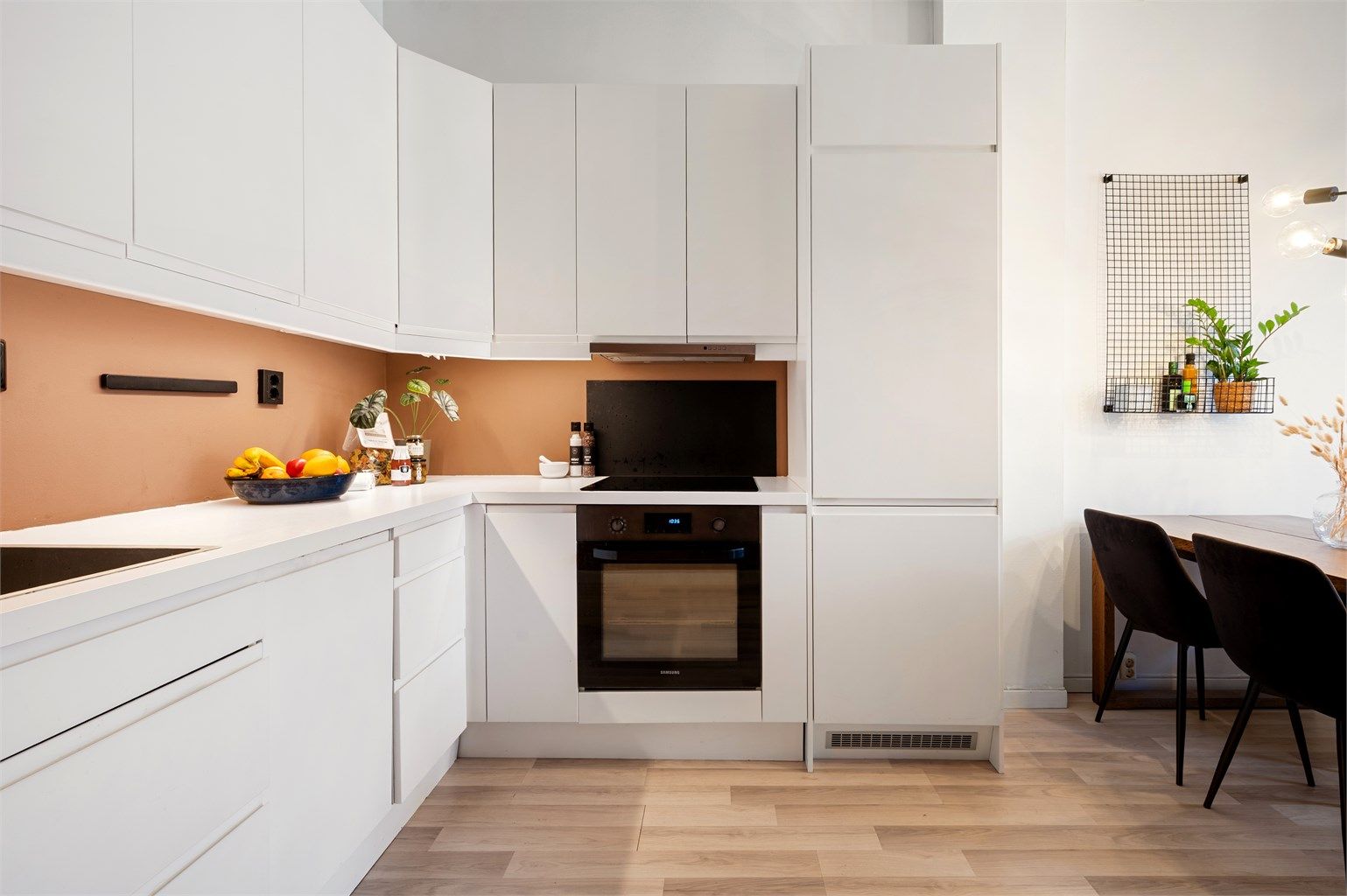 Videre er det plassert ventilator i overskap. Bak platetoppen/kjøkkenvasken er det montert en prakisk glassplate.