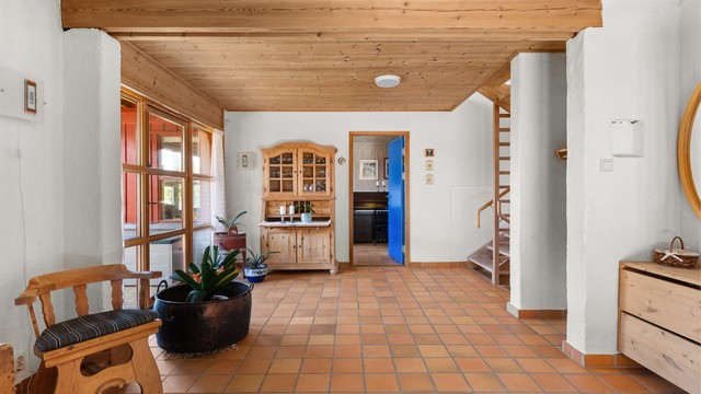 Hallen har mur yttervegger og panel i himling. Herfra er det utgang til en terrasse på 17 m².