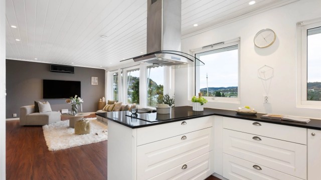 Kjøkkenhalvøy med platetopp og sitteplasser ved bardisken.