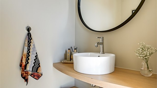 Toalettrommet har flislagt gulv, vegghengt toalett og servant. Veggene er nylig malt.