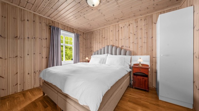 Soverom i første etasje med parkett på gulvet og panel på veggene.