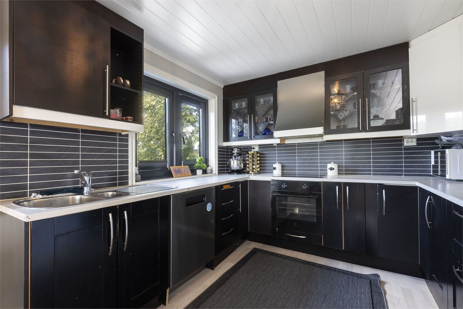 Kjøkken fra 2021/2022. Innredning med ett-speils og slette fronter. Laminert benkeplate benkeplate med nedsenket oppvaskkum i metall og ett-greps blandebatteri.