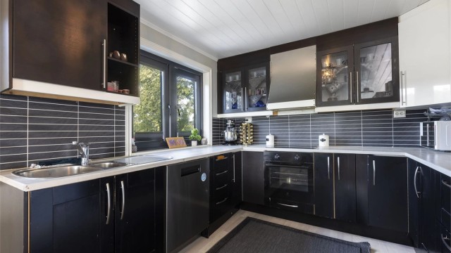 Kjøkken fra 2021/2022. Innredning med ett-speils og slette fronter. Laminert benkeplate benkeplate med nedsenket oppvaskkum i metall og ett-greps blandebatteri.