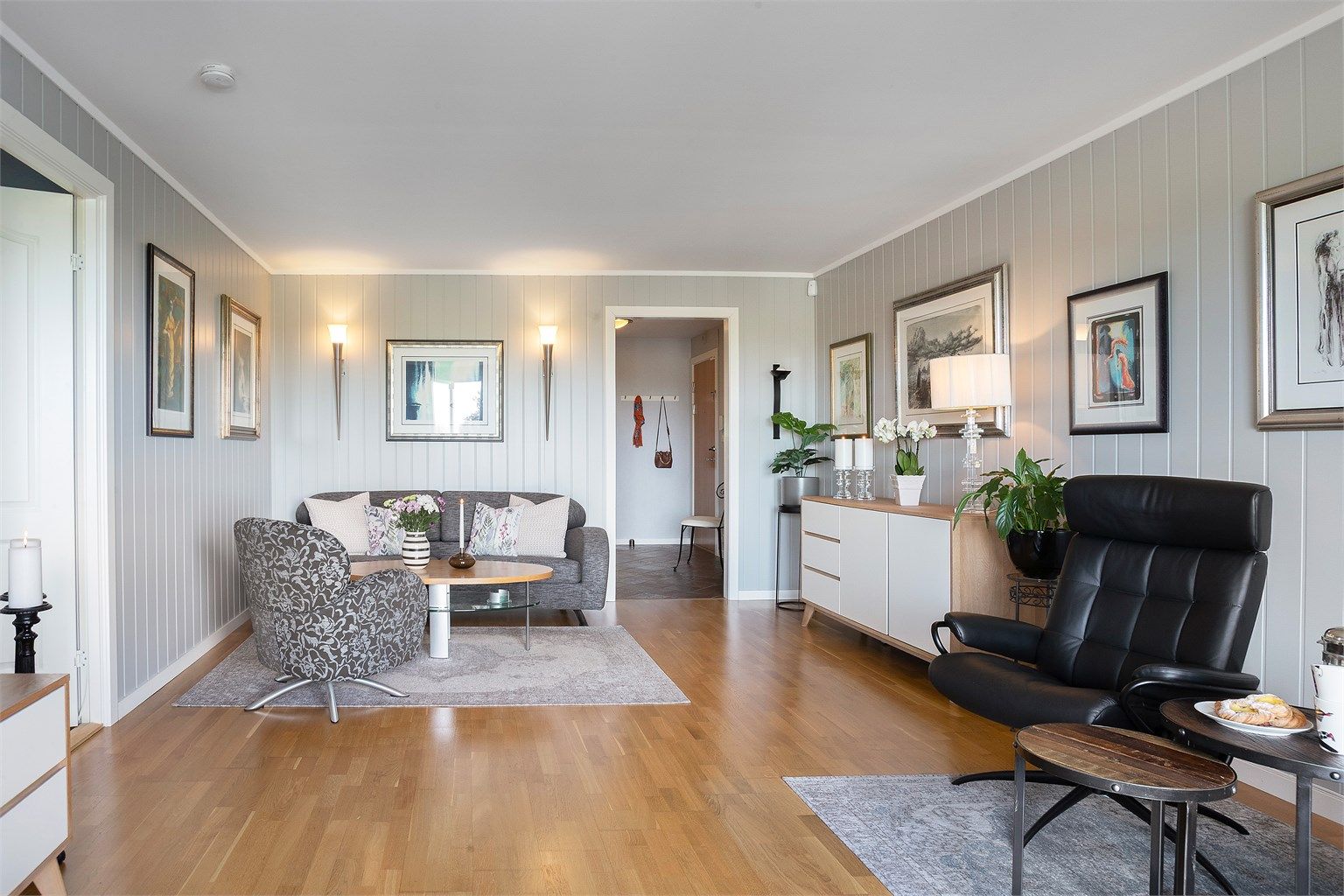 Stuen har god plass til sofagruppe og er utført med stående, malt mdf-panel på veggene.