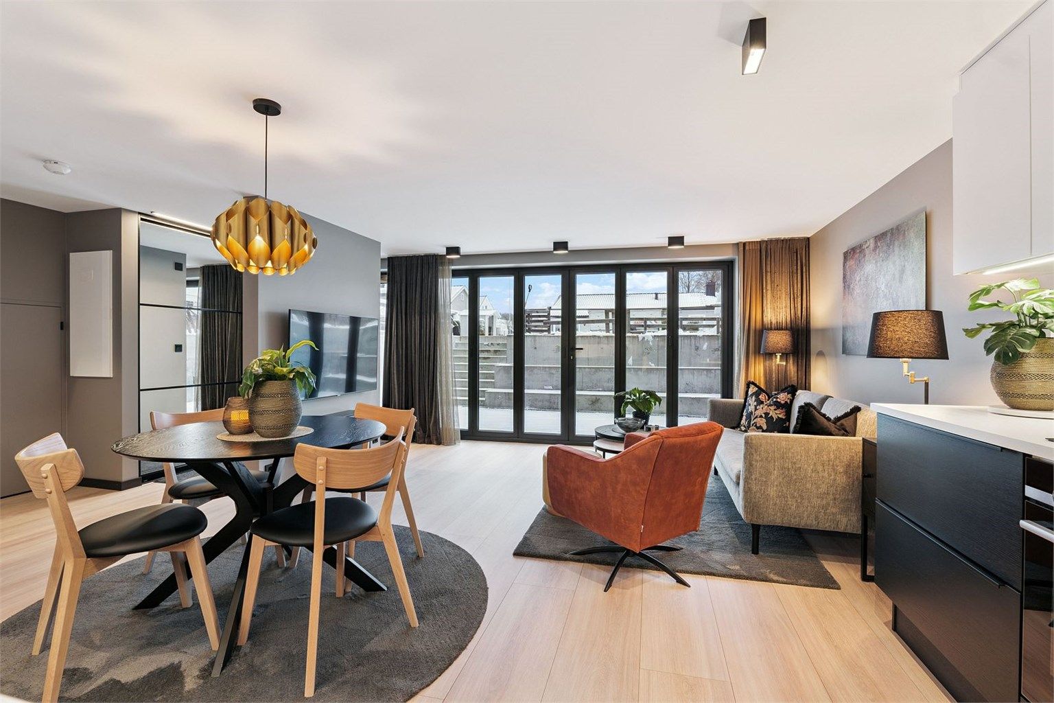 Stor og lys stue med åpen kjøkkenløsning, store foldedører som sikrer godt med naturlig belysning og tar deg ut til en 23 kvm privat uteplass.