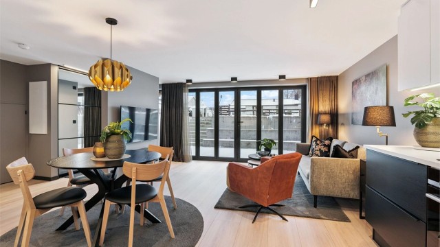 Stor og lys stue med åpen kjøkkenløsning, store foldedører som sikrer godt med naturlig belysning og tar deg ut til en 23 kvm privat uteplass.