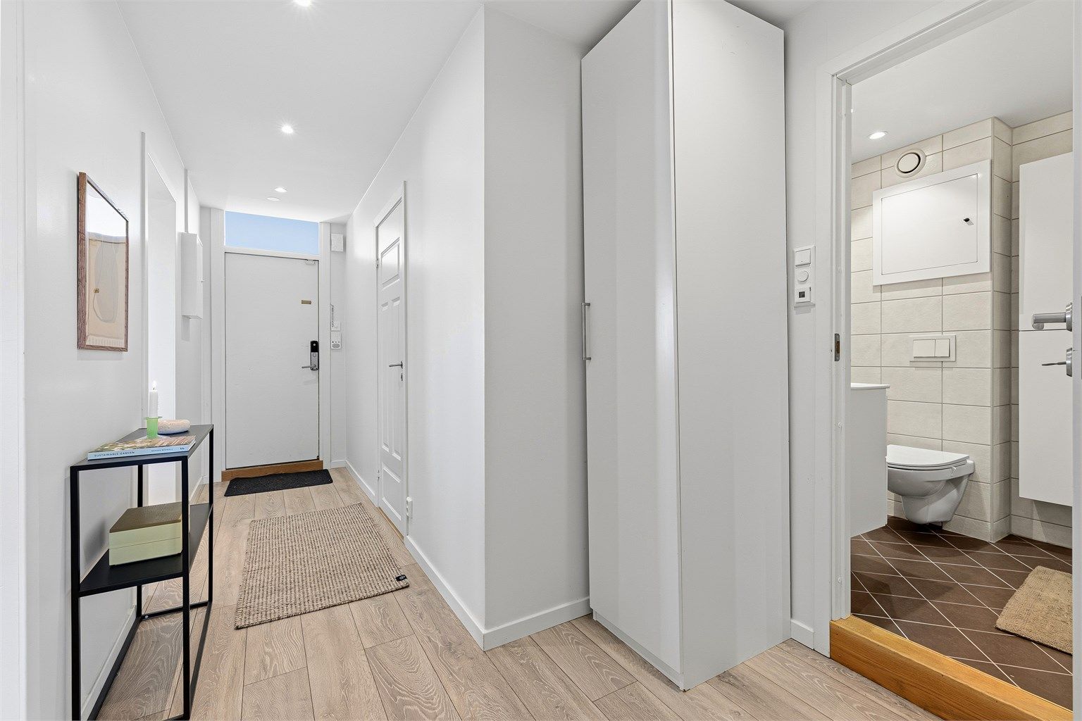 Velkommen inn i en lys gang, med god plass til å henge fra seg klær og sko.