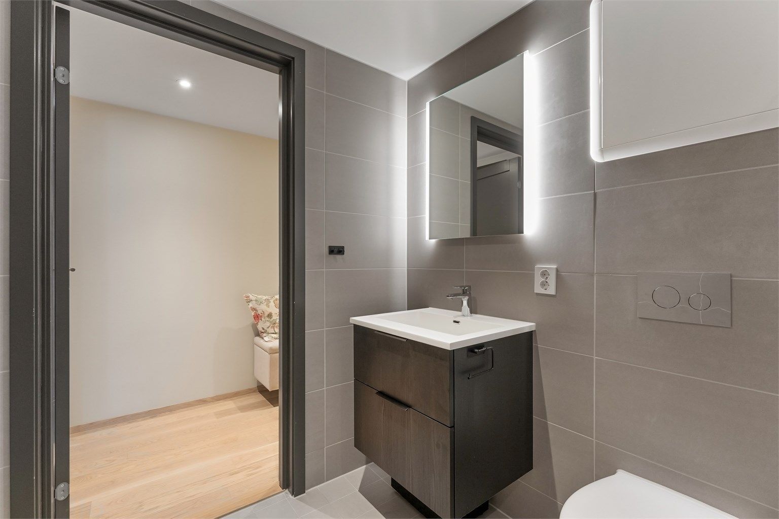 Badet har vannbåren gulvvarme, vegghengt toalett og dusjhjørne med innfellbare glassdører.