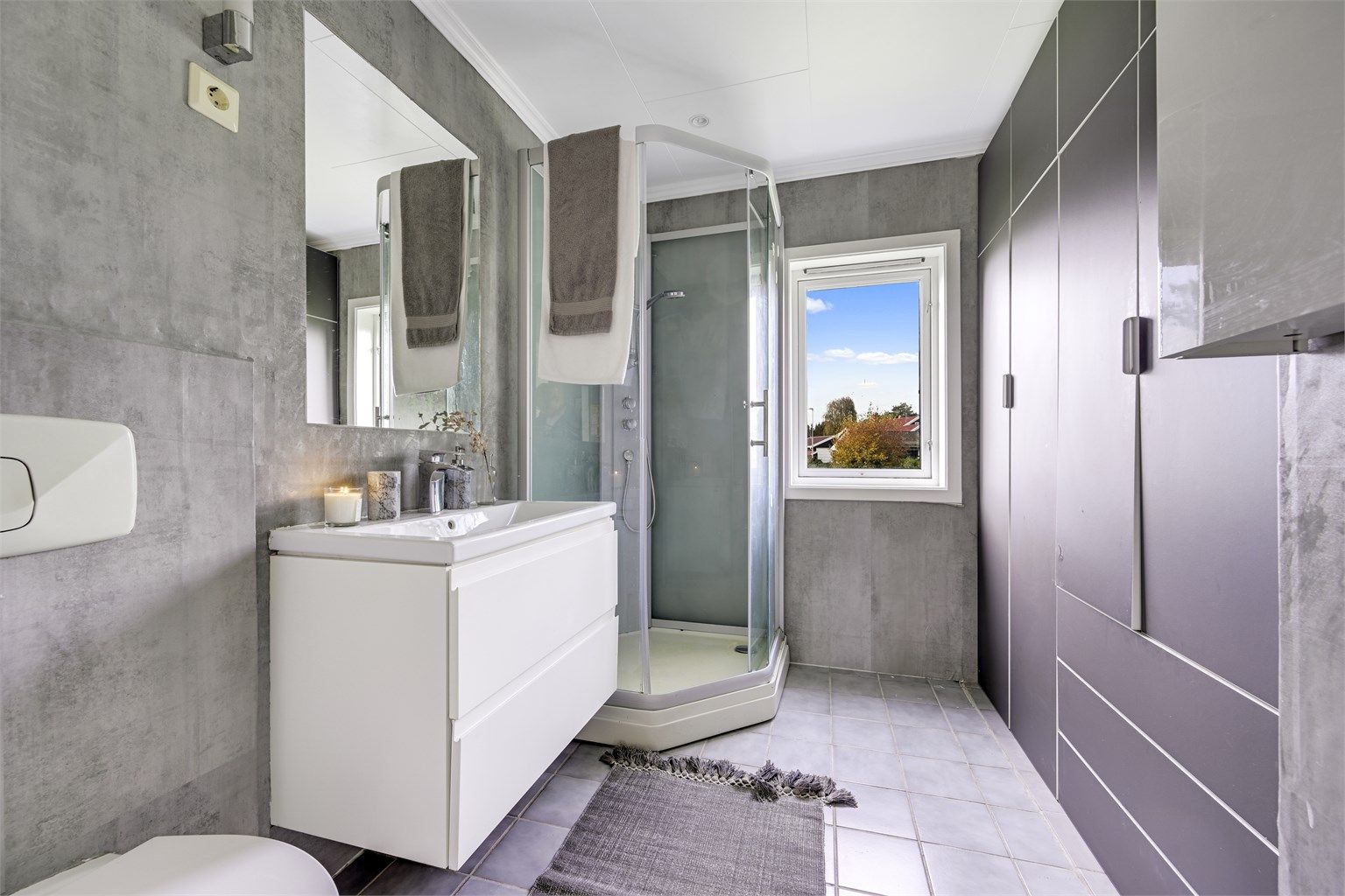 Badet i hovedetasjen har flislagt gulv med varmekabler og dusjkabinett.