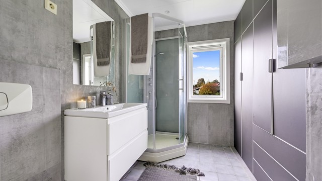 Badet i hovedetasjen har flislagt gulv med varmekabler og dusjkabinett.