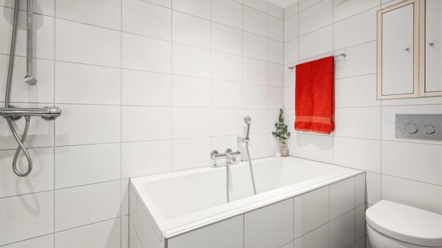 Badet fremstår lyst og delikat, og er praktisk innredet med både dusj og badekar.