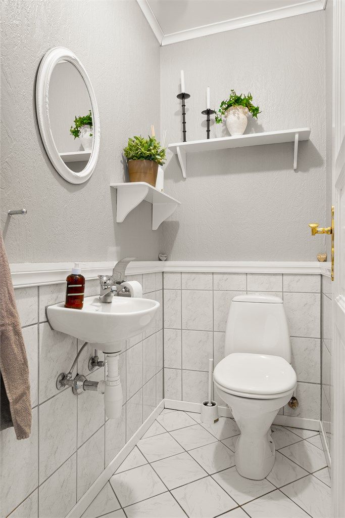 Praktisk toalettrom i hovedetasjen med flislagt gulv og vegghengt servant.
