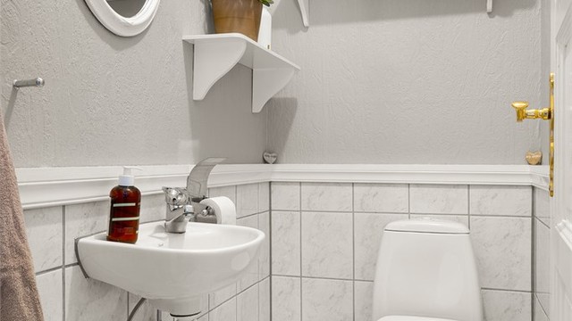 Praktisk toalettrom i hovedetasjen med flislagt gulv og vegghengt servant.