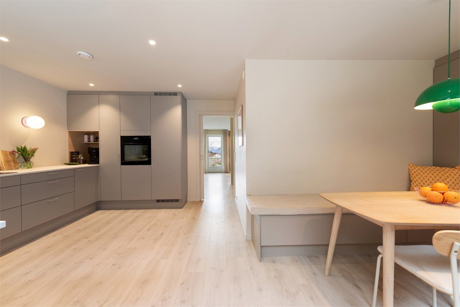 Kjøkkenet har en praktisk og sosial utforming med plassbygd sittebenk og spisebord.