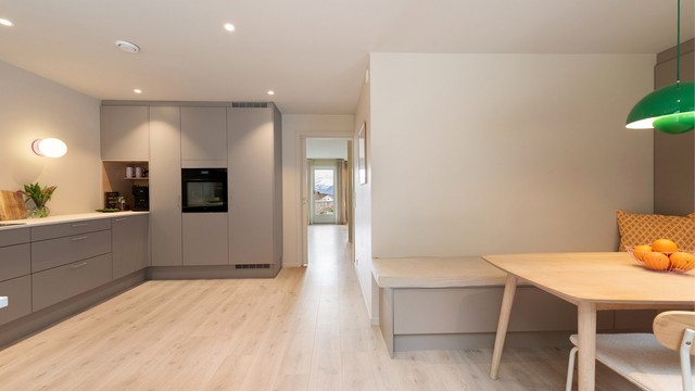 Kjøkkenet har en praktisk og sosial utforming med plassbygd sittebenk og spisebord.