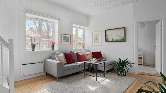 Lyset strømmer inn fra flere vinduer og gir rommet en lett og luftig atmosfære.